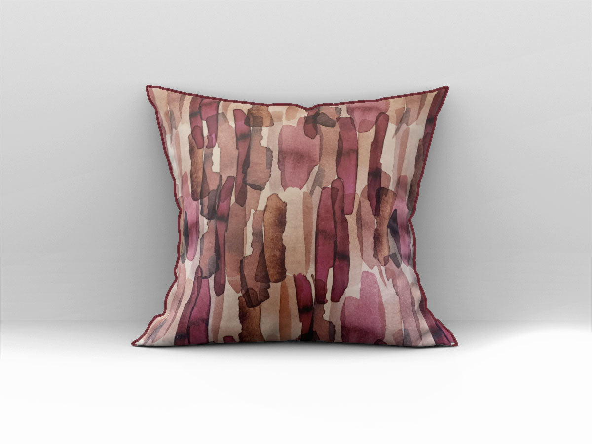 Decorative scatter cushion featuring a watercolour-inspired abstract pattern in blush pink, burgundy, rust, brown, and soft neutral tones, styled on a grey sofa.