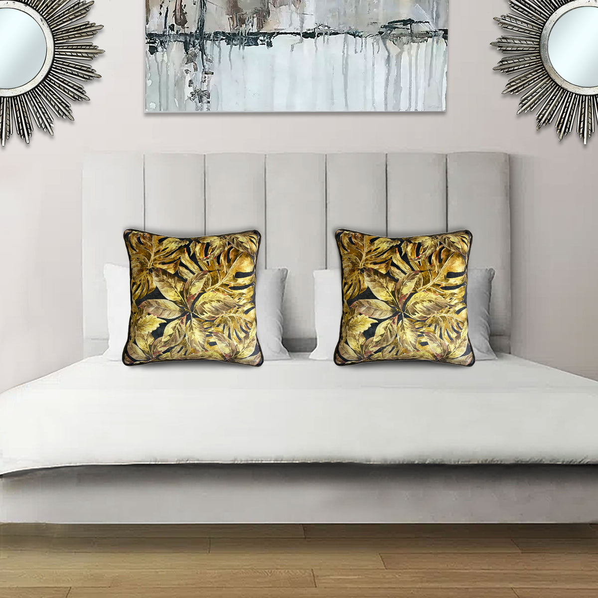Decorative scatter cushion featuring a rich tropical botanical leaf pattern in gold, mustard, black, and earthy tones, styled on an elegant upholstered bed.