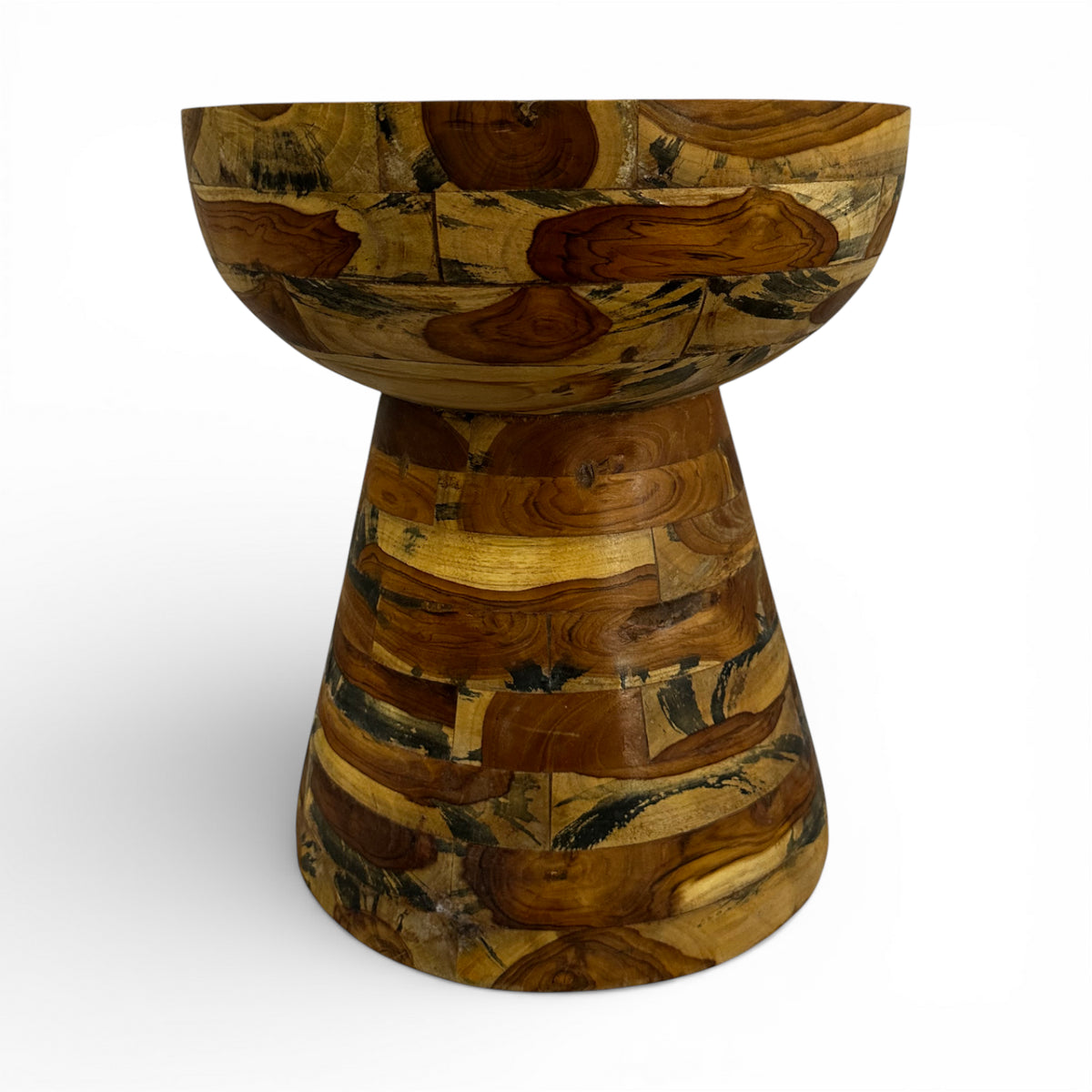 Handcrafted accent table featuring a sculptural hourglass silhouette crafted from solid teak wood in a patchwork design that highlights the natural grain and warm timber tones. A distinctive statement piece ideal as a side table, pedestal, or decorative accent for living rooms, boutique hotels, lodges, or contemporary rustic interiors.