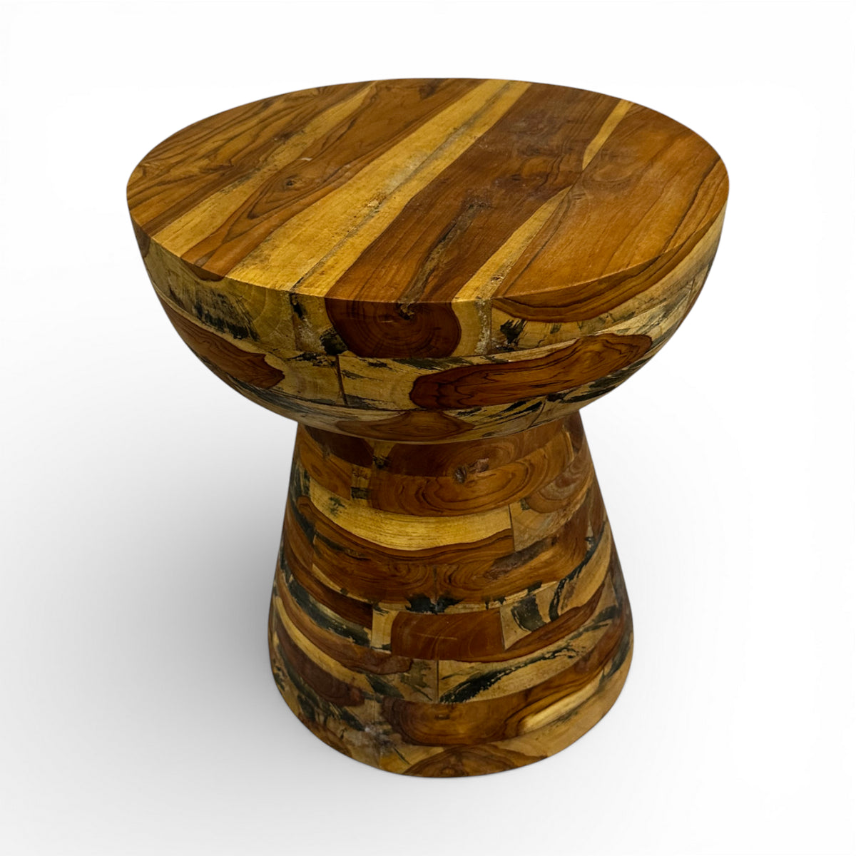 Handcrafted accent table featuring a sculptural hourglass silhouette crafted from solid teak wood in a patchwork design that highlights the natural grain and warm timber tones. A distinctive statement piece ideal as a side table, pedestal, or decorative accent for living rooms, boutique hotels, lodges, or contemporary rustic interiors.