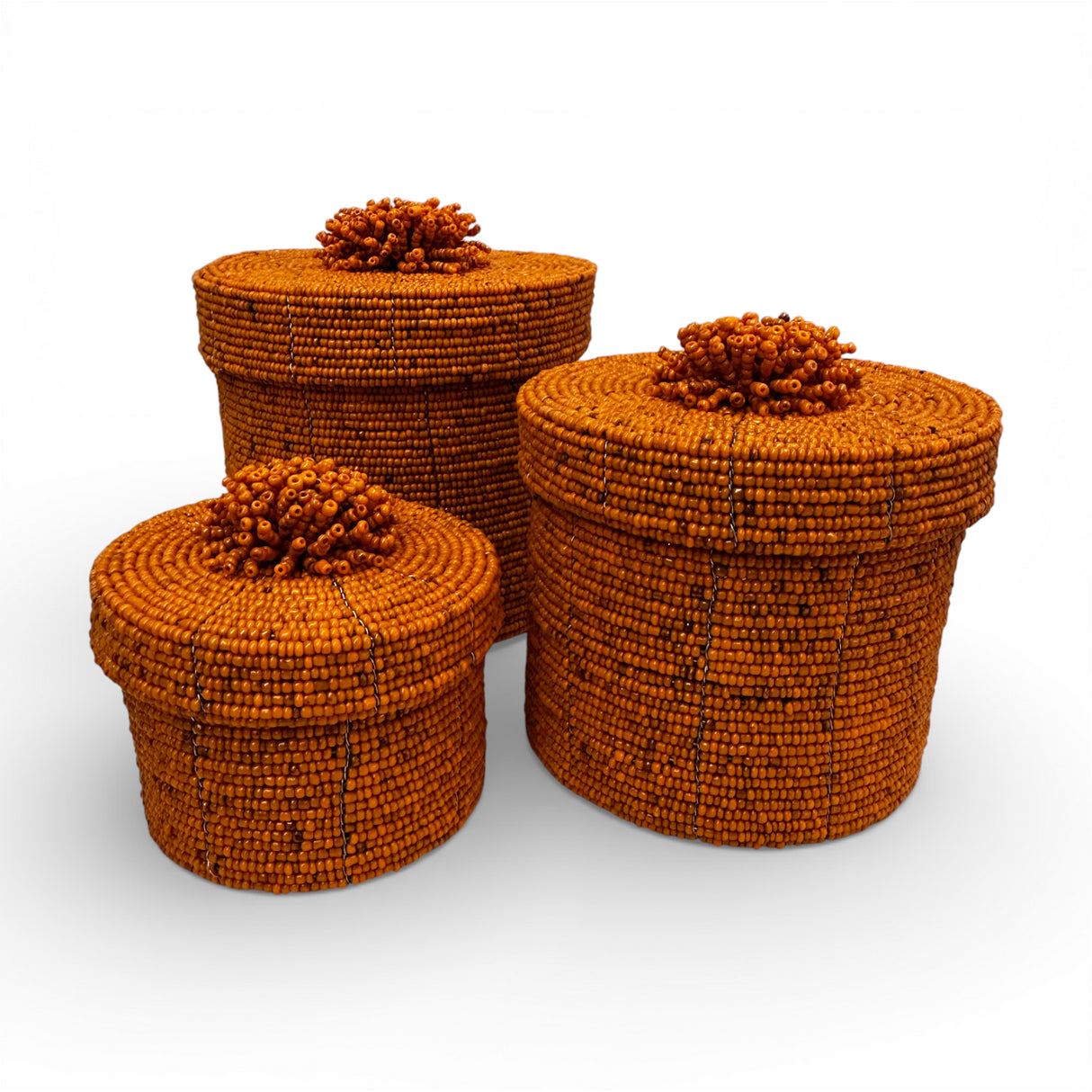 Set of three handcrafted cylindrical storage baskets with warm amber wooden beads, matching fitted lids, and decorative beaded handles, perfect for stylish storage and natural décor in living rooms, bedrooms, or bathrooms.
