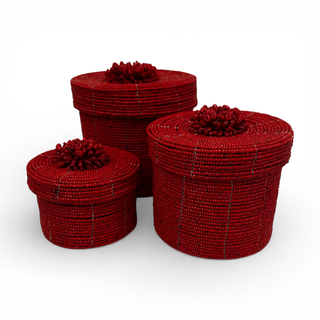 Set of three handcrafted cylindrical storage baskets with rich ruby red wooden beads, matching fitted lids, and decorative beaded handles, perfect for stylish storage and adding a bold decorative accent to living rooms, bedrooms, or bathrooms.