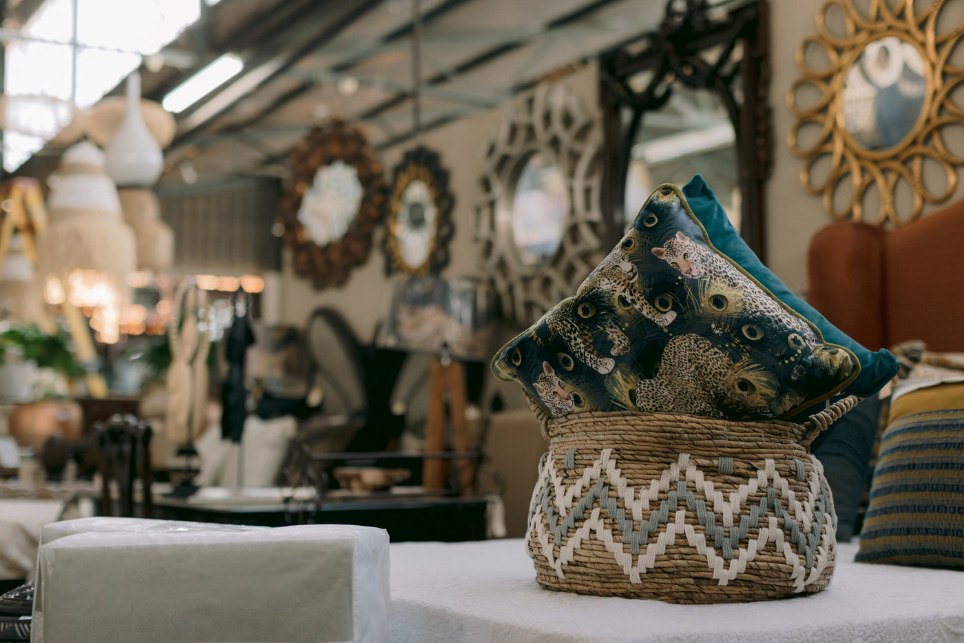 Decorative woven storage basket featuring a textured natural fibre finish with a grey and white geometric pattern, styled with a luxurious leopard-print scatter cushion and a solid teal velvet cushion. A stylish décor set for contemporary, safari-inspired, and luxury interiors.