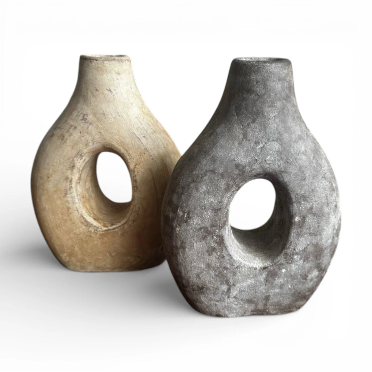 Set of two sculptural donut decorative vases featuring circular cut-out designs in natural sand and charcoal grey finishes. These handcrafted statement vases bring organic texture and contemporary style to shelves, consoles, coffee tables, and modern, boho, wabi-sabi, or Scandinavian interiors.
