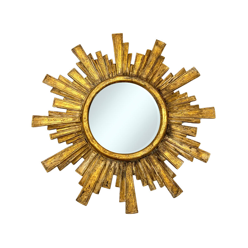 Decorative round wall mirror with an antique gold geometric sunburst frame featuring layered rectangular rays and a distressed metallic finish, perfect for elegant modern and classic interiors.