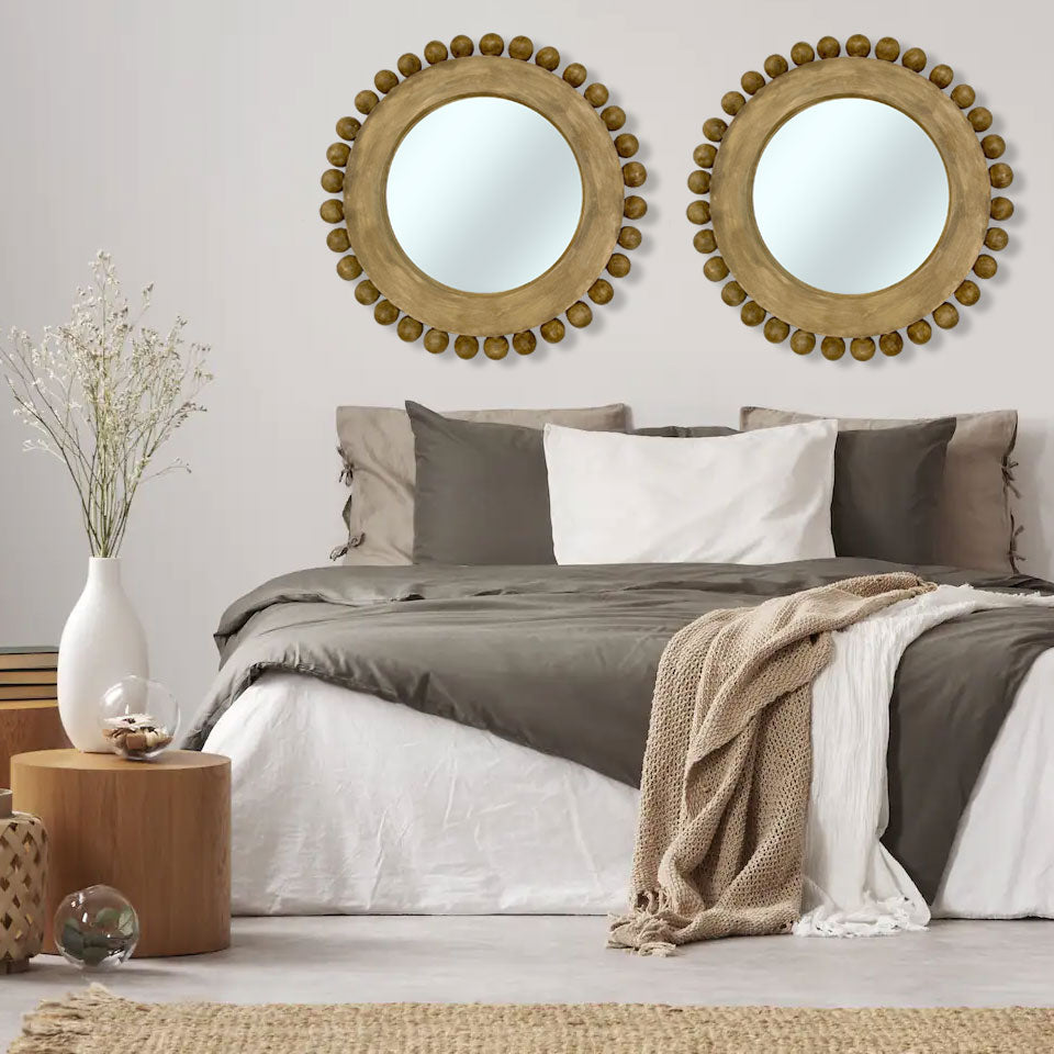 Set of two round gold beaded wall mirrors with distressed wooden frames, beautifully styled above a modern bed to create a warm, elegant focal point in a contemporary bedroom.
