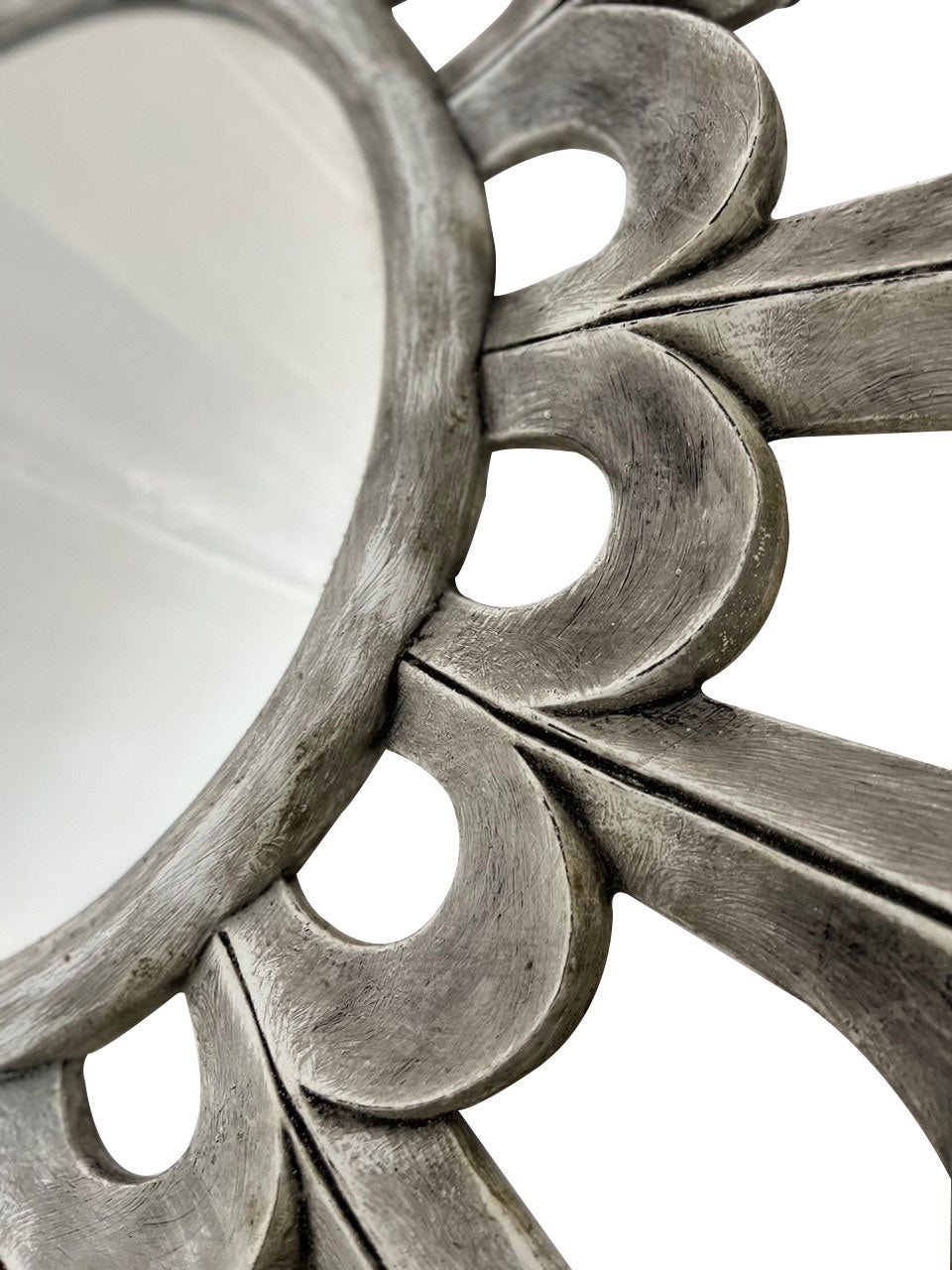 Close-up of a round wall mirror featuring sculptural petal detailing with a distressed silver finish, highlighting its handcrafted texture and elegant decorative design.