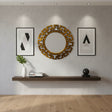 Round brushed gold geometric wall mirror with a bold Greek key-inspired frame, styled between modern framed artwork in a contemporary living room.