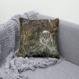 Decorative scatter cushion featuring elegant protea flowers and botanical leaves in black, charcoal, gold, and soft silver tones with coordinating gold piping.