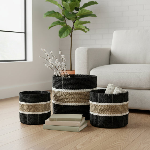 Set of three woven storage baskets featuring bold black, natural beige and cream horizontal stripes in varying sizes, styled in a modern living room.