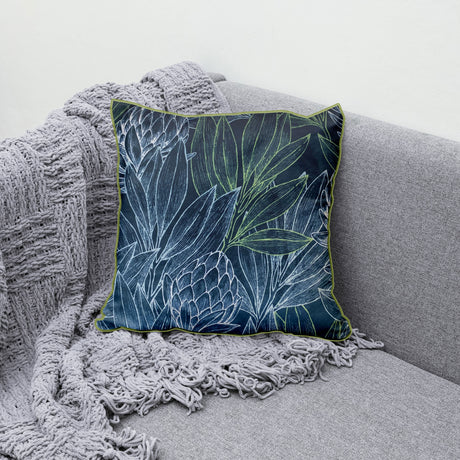 Decorative blue scatter cushion featuring an elegant protea and botanical leaf pattern with contrasting green piping, perfect for adding colour and texture to stylish interiors.