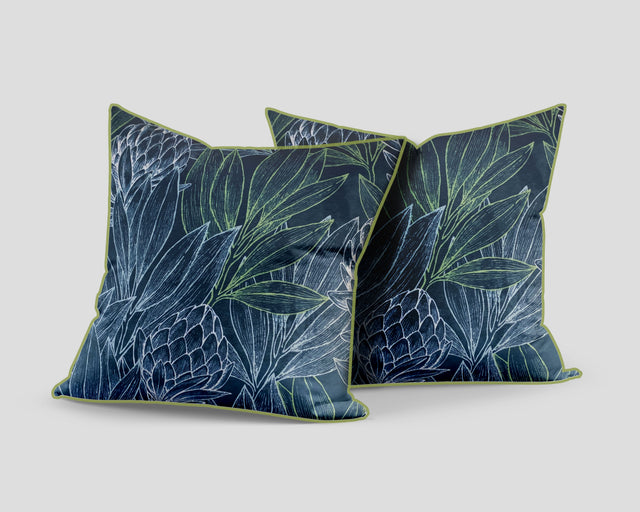 Decorative blue scatter cushion featuring an elegant protea and botanical leaf pattern with contrasting green piping, perfect for adding colour and texture to stylish interiors.