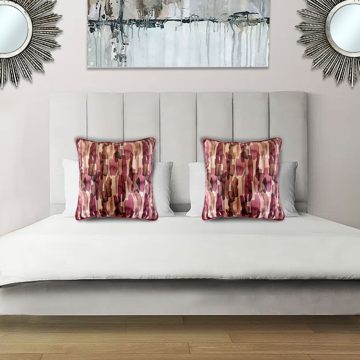Decorative scatter cushion featuring an abstract pattern in blush pink, burgundy, rust, and neutral tones, styled on an elegant upholstered bed.