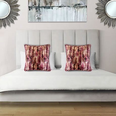 Decorative scatter cushion featuring an abstract pattern in blush pink, burgundy, rust, and neutral tones, styled on an elegant upholstered bed.