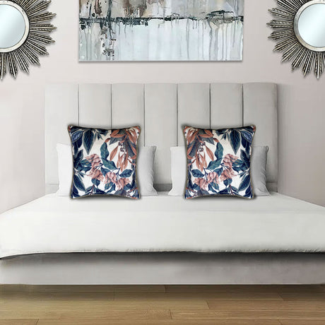Decorative scatter cushion featuring a botanical floral pattern in blush pink, navy blue, rust, and soft neutral tones, styled on an elegant upholstered bed.