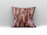 Decorative scatter cushion featuring a watercolour-inspired abstract pattern in blush pink, burgundy, rust, brown, and soft neutral tones, styled on a grey sofa.
