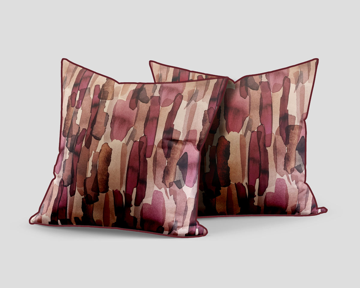 Set of three decorative scatter cushions featuring a watercolour-inspired abstract pattern in blush pink, burgundy, rust, brown, and soft neutral tones with coordinating piping.