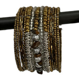 Handcrafted multi-layer wrap bracelet featuring bronze, silver, and clear seed beads with natural brown stone accents and textured metallic spacer beads, displayed wrapped around a black jewelry display rod.