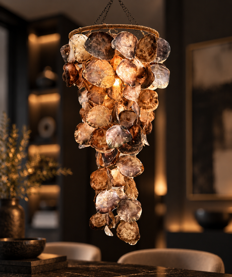 A hanging chandelier with a cluster of amber, bronze, and clear glass disc elements, illuminated from within in a dark, elegant dining room setting.
