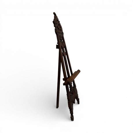 Traditional carved wooden display easel in a rich dark wood finish, featuring intricate ornamental detailing and an adjustable support, perfect for displaying artwork, mirrors, wedding signage, menus, or decorative pieces.