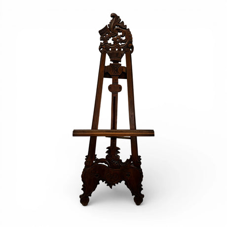Traditional carved wooden display easel in a rich dark wood finish, featuring intricate ornamental detailing and an adjustable support, perfect for displaying artwork, mirrors, wedding signage, menus, or decorative pieces.