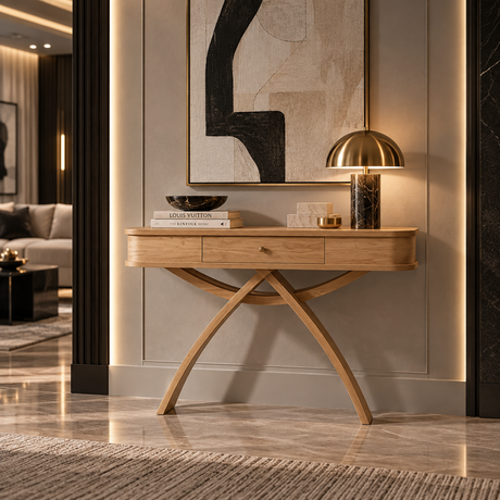 A modern light oak console table with a single drawer and sculptural curved legs, styled in a luxury interior with a gold dome lamp, books, and abstract wall art.