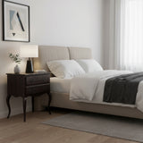 Neatly made bed in a bedroom with a side table and lamp.