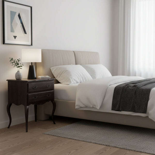 Neatly made bed in a bedroom with a side table and lamp.