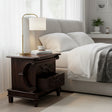 Elegant dark wood bedside table featuring two drawers, ornate carved detailing, decorative curved side accents, and turned wooden feet.