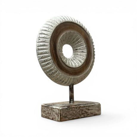 Decorative carved wooden ring sculpture mounted on a sturdy stand, featuring intricate radial detailing in distressed natural wood tones. A contemporary tabletop accent that adds texture and elegance to modern, Scandinavian, rustic, and minimalist home décor.