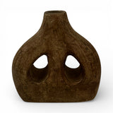 Handcrafted sculptural stoneware vase in a rich earthy brown finish, featuring a rounded organic silhouette, two asymmetrical cut-out openings, and a tapered neck. A bold contemporary decorative piece that adds warmth, texture, and artistic character to shelves, console tables, coffee tables, or styled interiors.