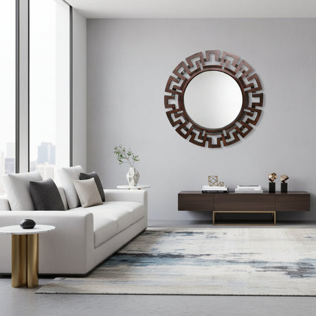 Round espresso-finish geometric wall mirror with a bold Greek key-inspired frame, styled above a modern console table with decorative accessories in a contemporary interior.