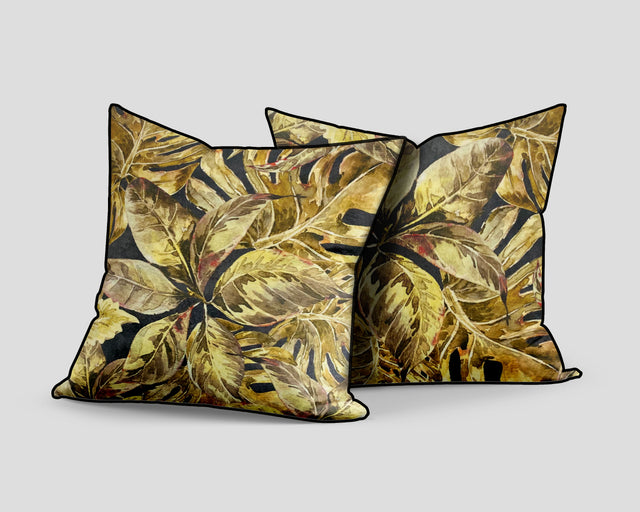 Set of three decorative scatter cushions featuring a rich tropical leaf pattern in gold, mustard, olive, and charcoal tones with contrasting dark piping.