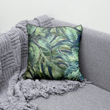 Decorative scatter cushion featuring a lush tropical leaf pattern in layered green, sage, and deep blue tones with coordinating dark green piping.