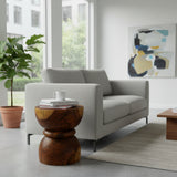 Handcrafted sculptural side table crafted from solid teak wood, featuring a smooth rounded tabletop and an elegant hourglass pedestal base that highlights the rich natural wood grain. A timeless statement piece perfect for living rooms, bedrooms, boutique hotels, lodges, or contemporary luxury interiors.