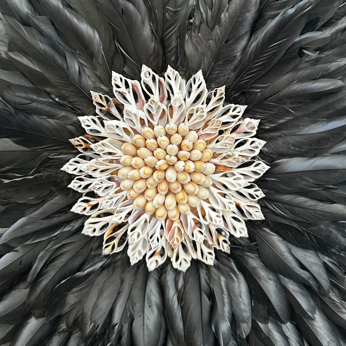 Decorative item with black feathers and a central beige flower-like design