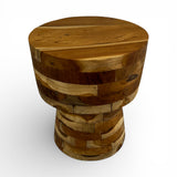Handcrafted round side table crafted from solid teak wood with a sculptural hourglass pedestal base. Showcasing a unique patchwork of natural timber grain and warm wood tones, this contemporary accent table is perfect for living rooms, bedrooms, boutique hotels, lodges, or modern rustic interiors.