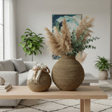 Handwoven natural decorative vases with sculptural rounded silhouettes, beautifully styled with pampas grass, eucalyptus, and soft furnishings on a wooden coffee table, adding warm organic texture and timeless elegance to contemporary interiors.
