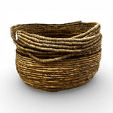 Handwoven natural storage basket with integrated carry handles and a soft organic silhouette, perfect for storing blankets, cushions, toys, or everyday essentials while adding warm texture and artisanal style to contemporary, coastal, or rustic interiors.