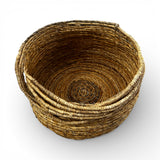 Handwoven natural storage basket with a rounded silhouette, integrated carry handles, and a tightly woven interior, ideal for storing blankets, cushions, toys, or everyday essentials while adding warm organic texture and timeless artisanal style to contemporary, coastal, or rustic interiors.