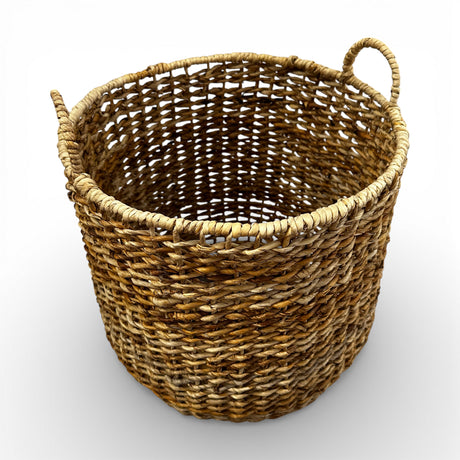 Handwoven natural storage basket with an open-weave design, integrated carry handles, and a soft organic silhouette, perfect for storing blankets, cushions, toys, or everyday essentials while adding warm texture and timeless artisanal style to contemporary, coastal, and rustic interiors.