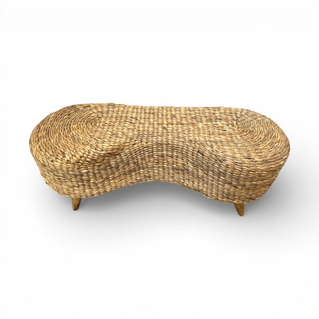 Handwoven natural rattan bench with a sculptural curved silhouette, rounded edges, and solid wooden legs, combining artisanal craftsmanship with warm organic texture for stylish seating in entryways, bedrooms, living rooms, or covered outdoor spaces.