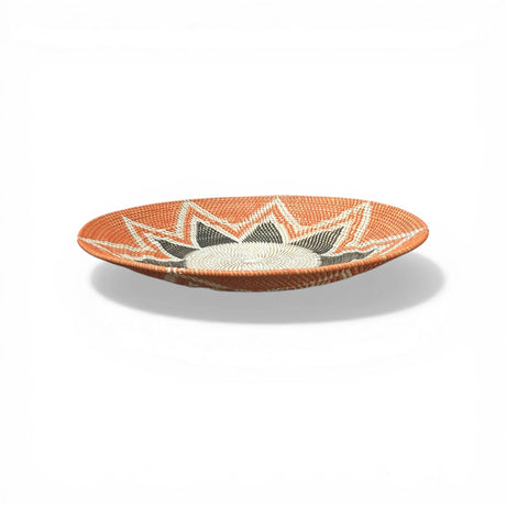Handwoven decorative bowl featuring a striking sunburst pattern in terracotta, cream, grey, and black. This handcrafted woven bowl adds warmth and texture to coffee tables, dining tables, consoles, and shelves in boho, contemporary, African-inspired, or rustic interiors.
