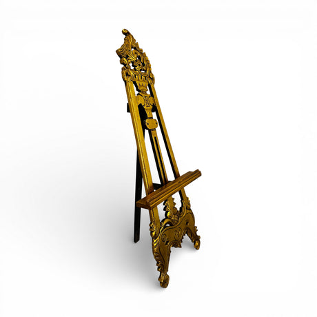 Elegant antique-style wooden display easel with ornate carved detailing and a distressed gold finish, featuring an adjustable support for showcasing artwork, mirrors, welcome signs, menus, or decorative displays.