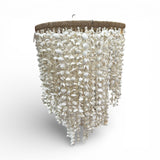 Handcrafted cascading chandelier featuring hundreds of natural white seashells suspended from a woven circular frame. This elegant coastal-inspired pendant light creates a soft, organic statement, making it perfect for dining rooms, living spaces, boutique hotels, beach homes, luxury lodges, or contemporary interiors.