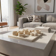 Luxury marble tic-tac-toe decorative set featuring carved stone X and O pieces on a solid marble board, styled on a modern coffee table with books in a contemporary living room.