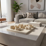 Luxury marble tic-tac-toe decorative set featuring carved stone X and O pieces on a solid marble board, styled on a modern coffee table with books in a contemporary living room.