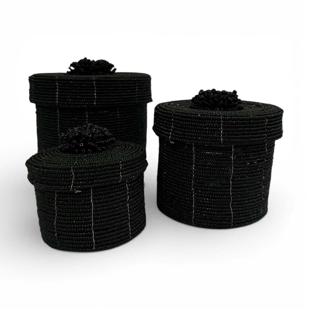 Set of three handcrafted cylindrical storage baskets with matte black wooden beads, matching fitted lids, and decorative beaded handles, perfect for stylish storage and adding a bold contemporary accent to living rooms, bedrooms, or bathrooms.