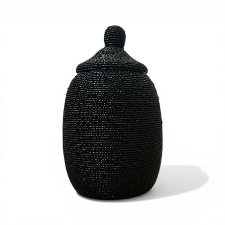 Handcrafted decorative urn featuring a matte black beaded finish with a matching fitted lid and rounded finial. A sophisticated artisan décor piece that adds texture, elegance, and contemporary African-inspired style to consoles, shelves, coffee tables, and luxury interiors.