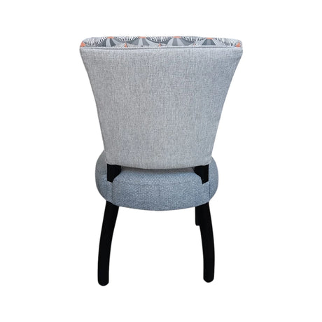 Modern upholstered dining chair with a soft grey fabric seat, an Art Deco-inspired patterned backrest in grey, charcoal and muted terracotta tones, and sleek black wooden legs. Perfect for contemporary dining rooms, restaurants, and luxury interiors.